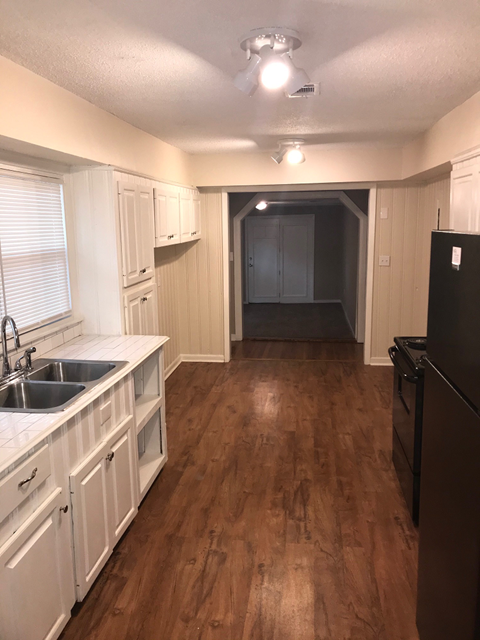 A kitchen with wooden floors and white cabinets.