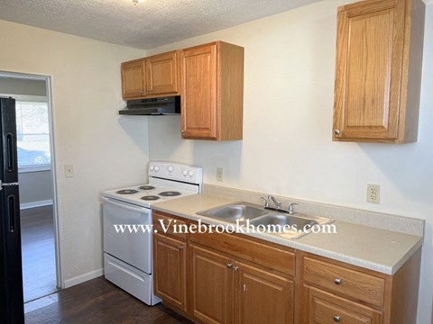 A kitchen with wooden cabinets and a white stove top oven.