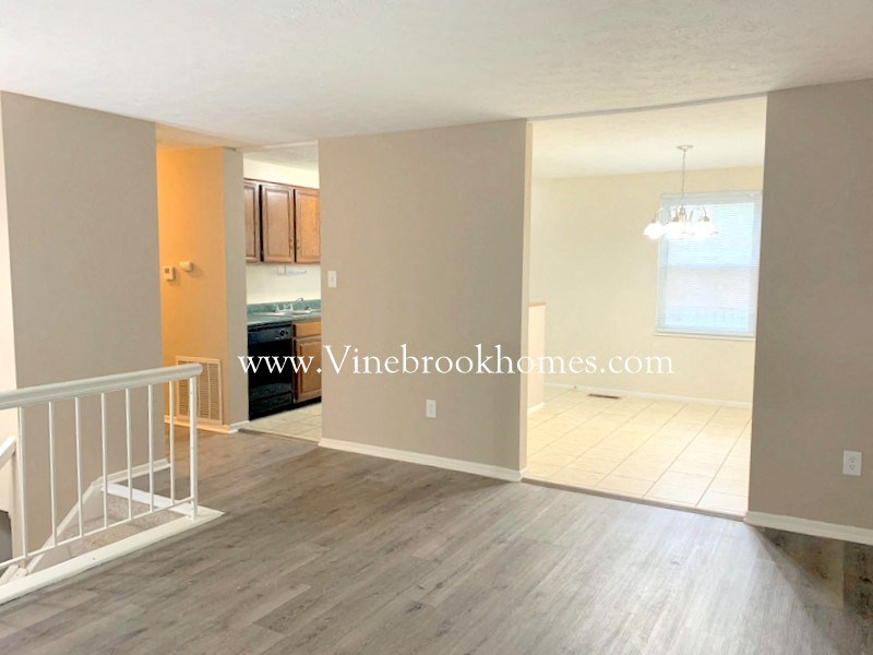 an empty living room and dining room with a staircase