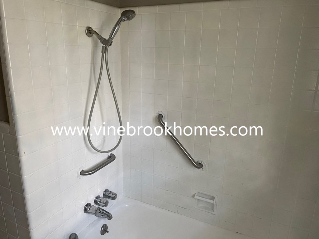 a white tiled shower in a bathroom with chrome fixtures