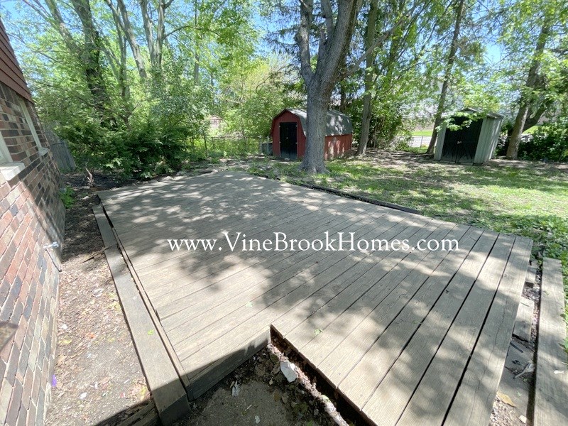 a backyard with a wooden deck and a red shed