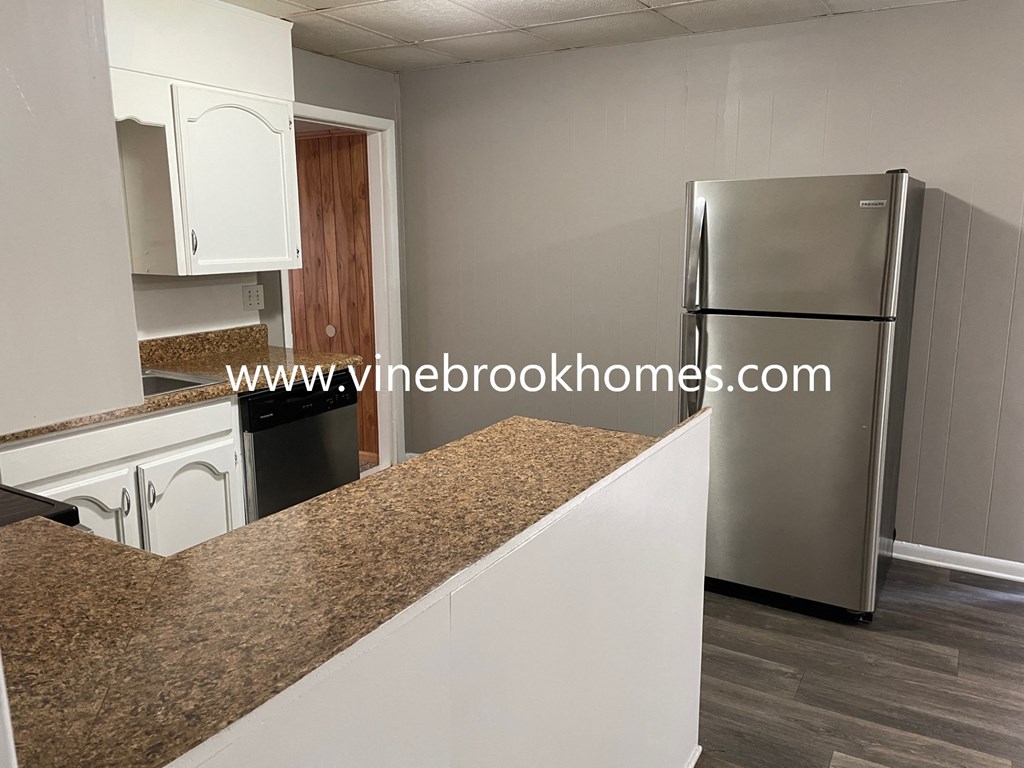 a kitchen with white cabinets and a stainless steel refrigerator