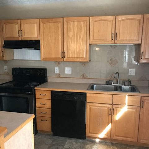 A kitchen with wooden cabinets and black appliances.