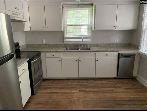 A kitchen with white cabinets and a wooden floor.