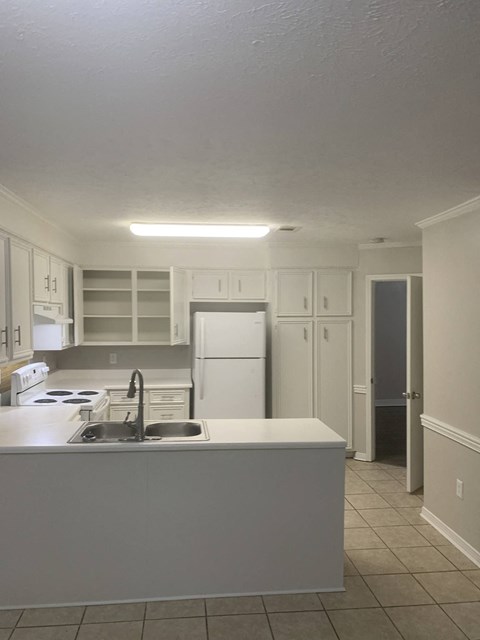 an empty kitchen with a sink and a refrigerator