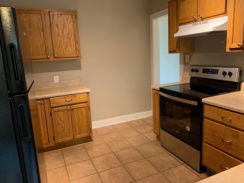 A kitchen with wooden cabinets and a black refrigerator.