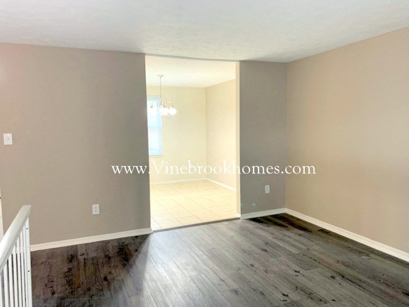 an empty living room with wood floors and a door to a hallway