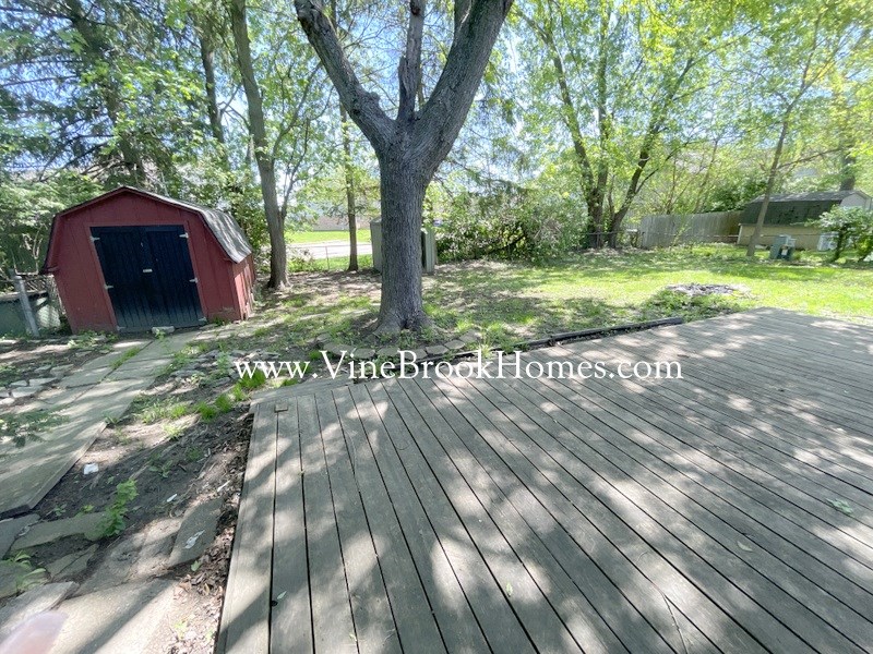 a large deck with a tree and a red shed