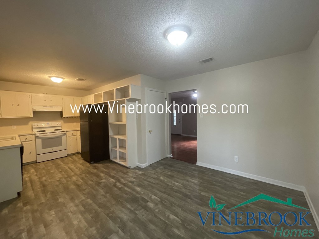 a kitchen and living room with a hard wood floor and white cabinets