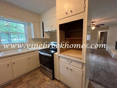 a kitchen with white cabinets and an oven and a window