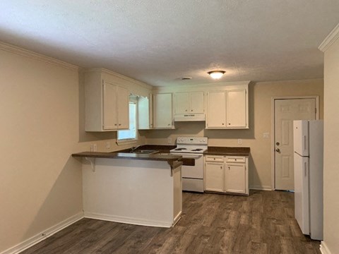 A kitchen with white appliances and wooden floors.