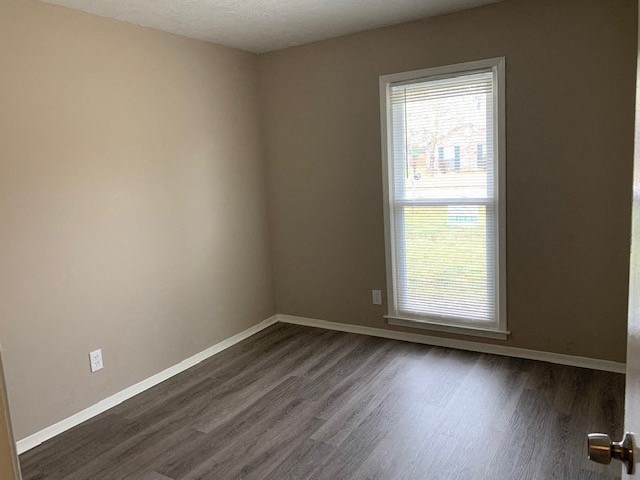 an empty room with a window and wooden floors