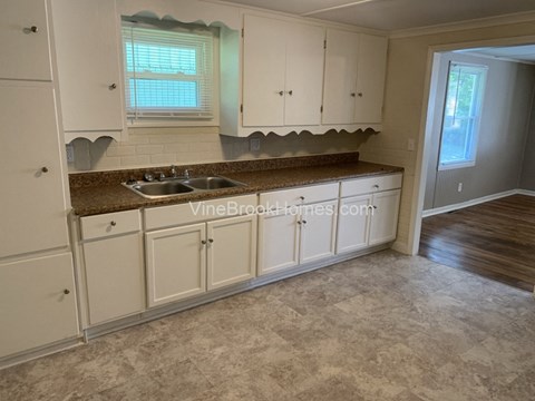 A kitchen with white cabinets and a brown countertop.