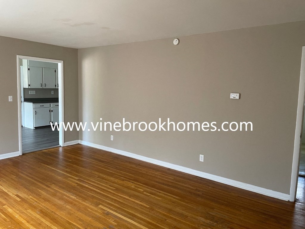 a small living room with a wooden floor and a kitchen