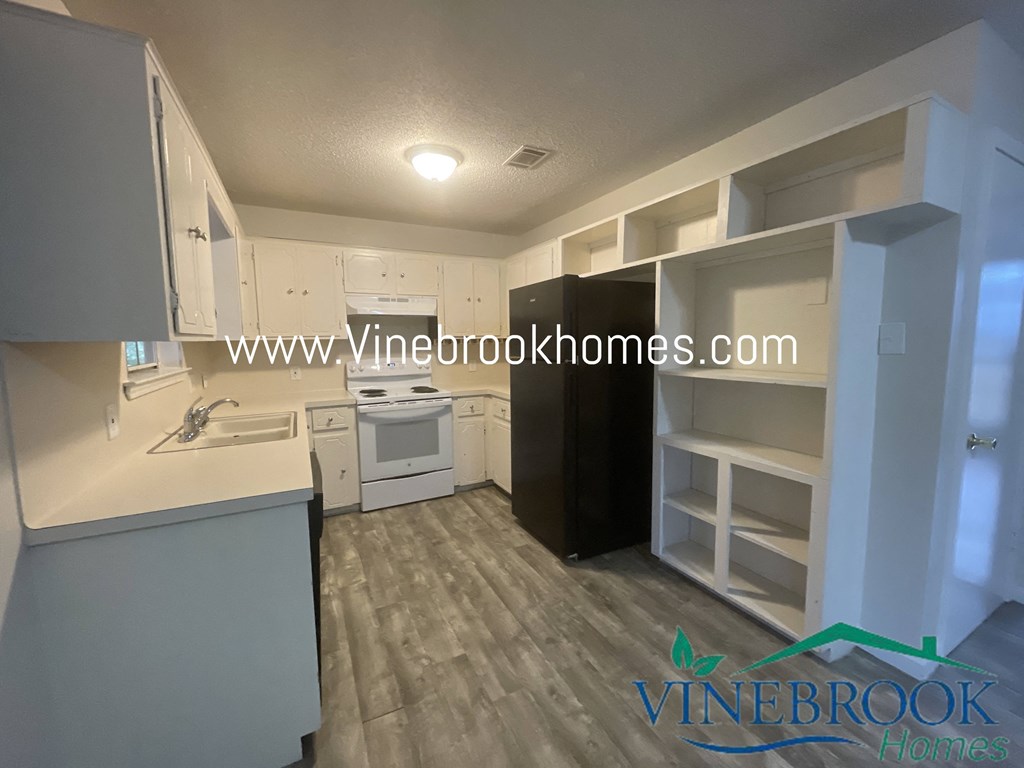 a kitchen with white cabinets and white appliances and a wood floor