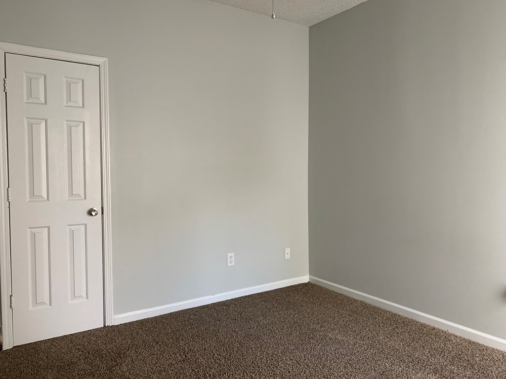 an empty room with a white door and carpet