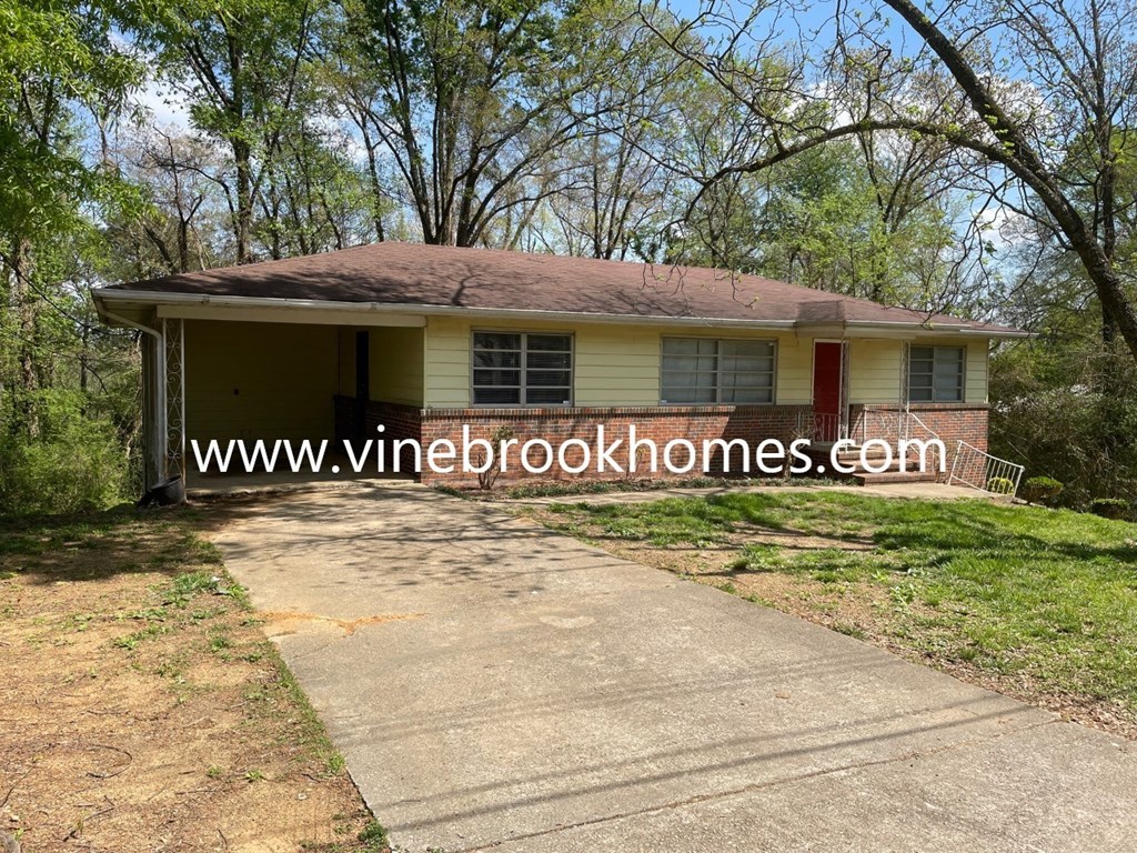 a small house with a driveway and trees