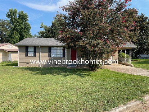a small tan house with a tree in front of it