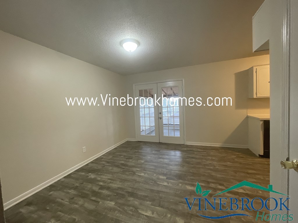 a living room with a hard wood floor and a door to a kitchen