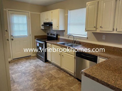 A kitchen with a granite counter top and white cabinets.