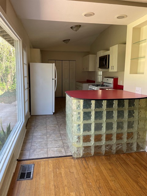A kitchen with a white fridge and a red counter.