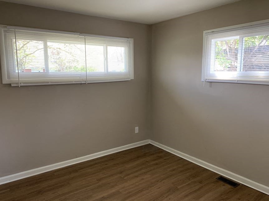 a empty room with two windows and a wooden floor