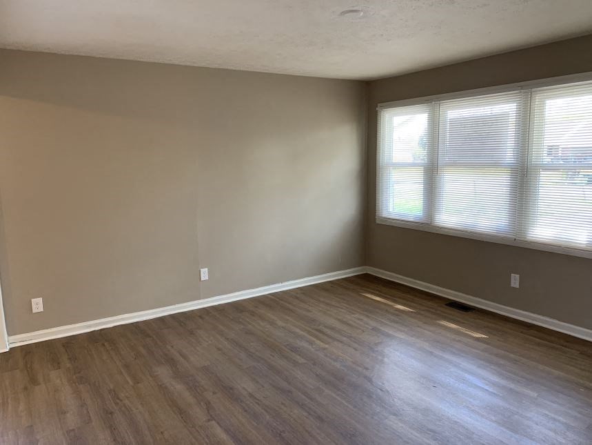 an empty living room with wood floors and a window