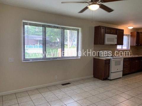 A kitchen with a fan and a window with blinds.