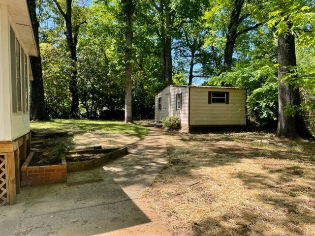 a small house in the woods with a yard and a driveway