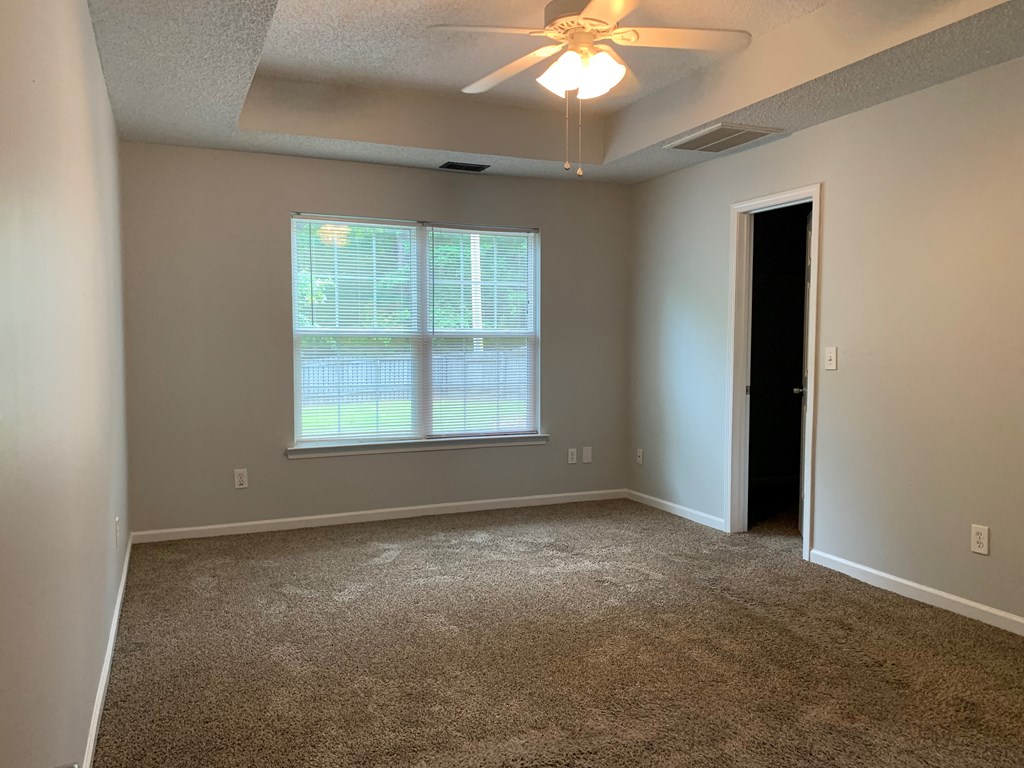 an empty living room with a window and a ceiling fan