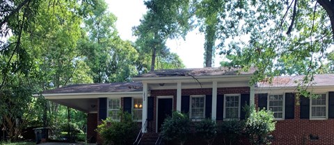 A red brick house with a porch and a covered front door.