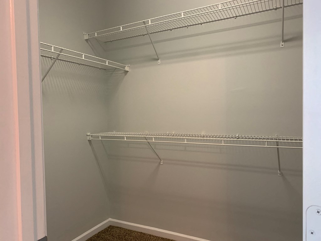 a walk in closet with an empty shelf in it