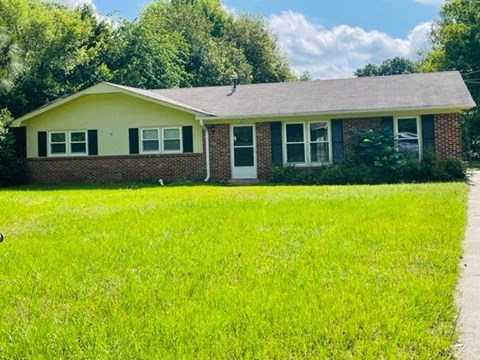 a small brick house with a yard in front of it