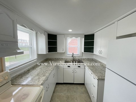 A kitchen with white cabinets and a granite countertop.