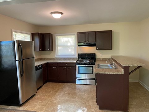 A kitchen with brown cabinets and a black refrigerator.
