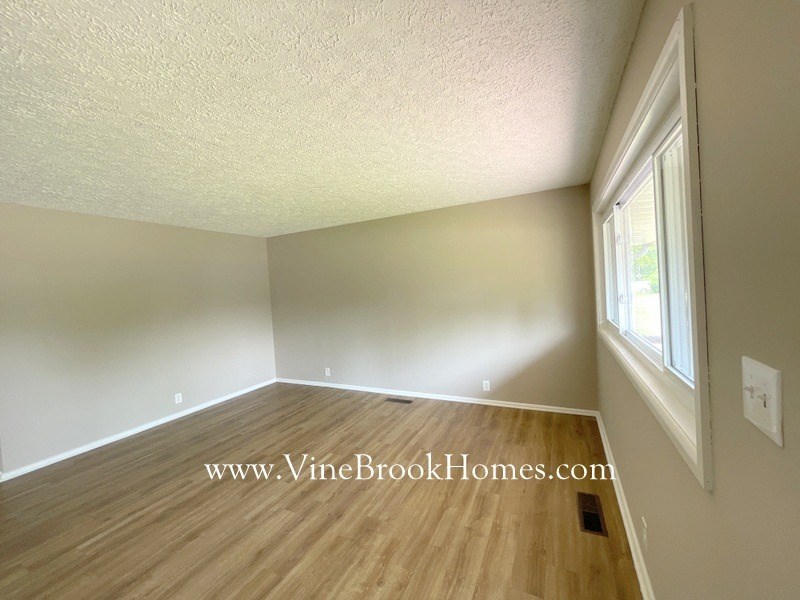 an empty living room with wood flooring and a large window
