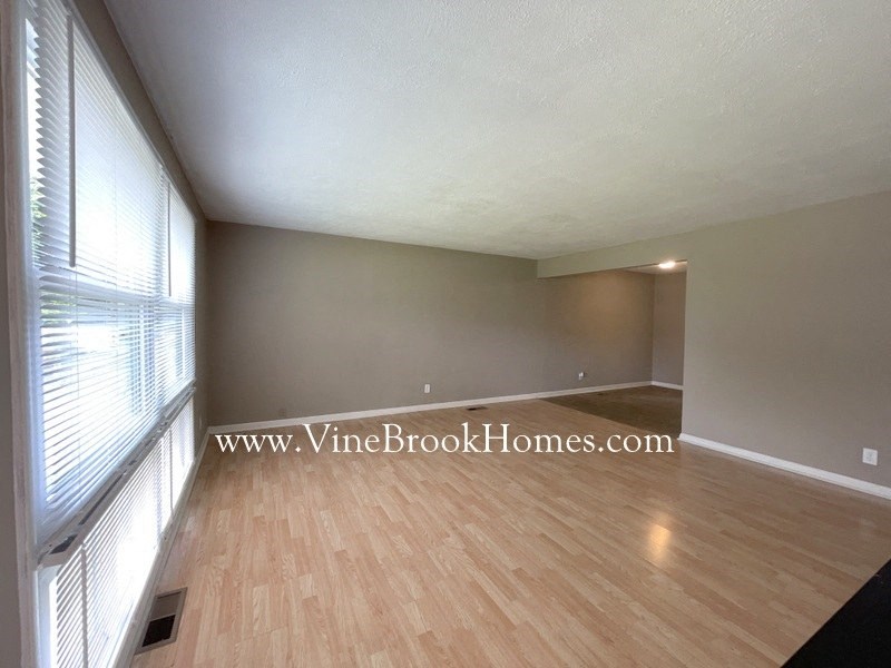 an empty living room with wood floors and a window