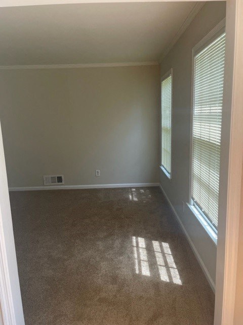 an empty room with two windows and a carpet