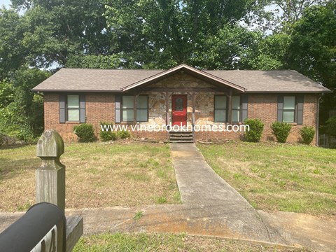 the front of a brick house with a red door