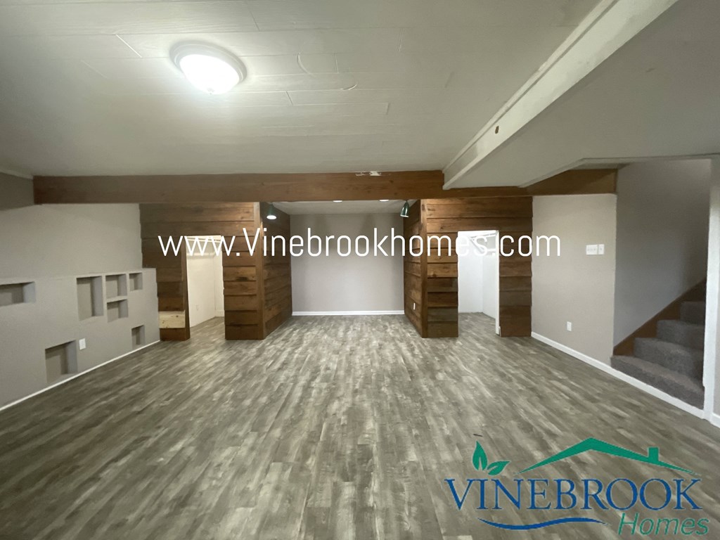 a large living room with wood floors and a staircase