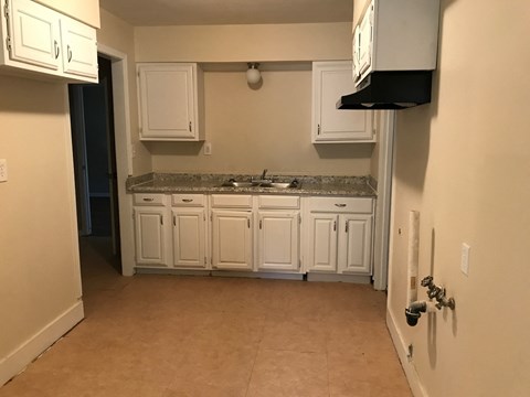 A kitchen with white cabinets and a granite countertop.