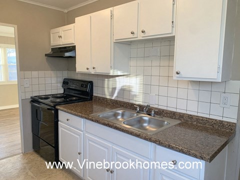 A kitchen with white cabinets and a black stove top oven.