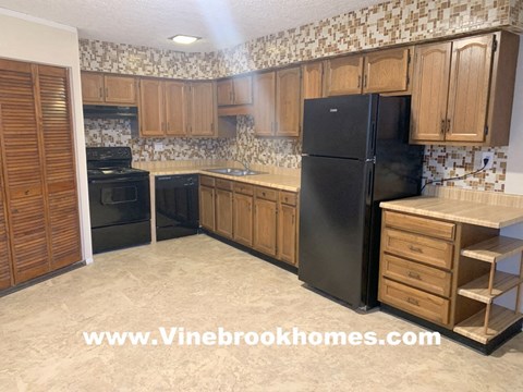 A kitchen with wooden cabinets and a black refrigerator.