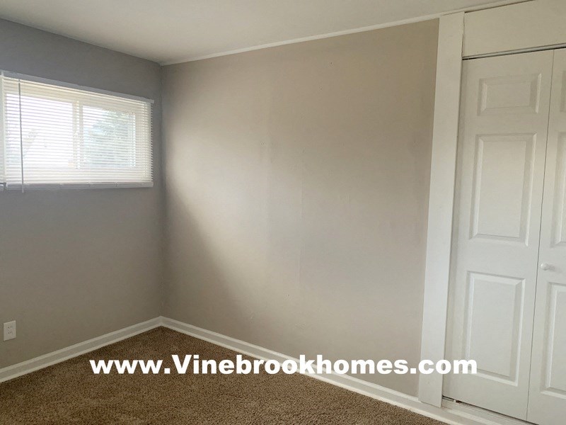 a small room with white walls and a window and a closet