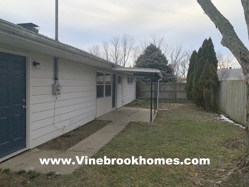 a backyard of a white house with a yard and a porch