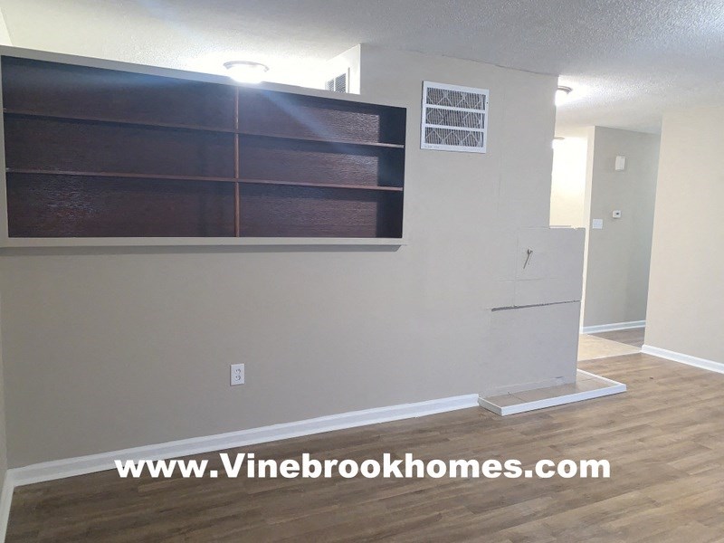 an empty living room with a white wall and wood flooring