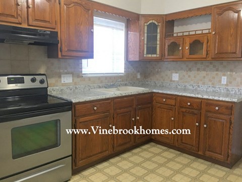 A kitchen with wooden cabinets and a black stove top oven.