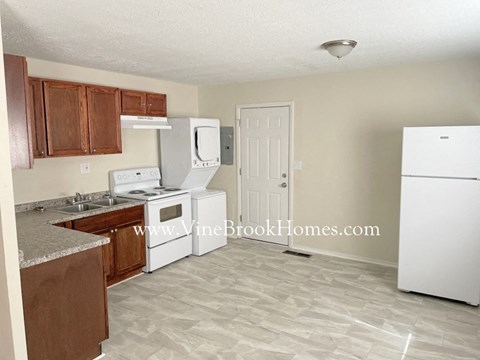 A kitchen with white appliances and wooden cabinets.
