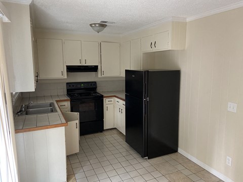 A kitchen with black appliances and white cabinets.