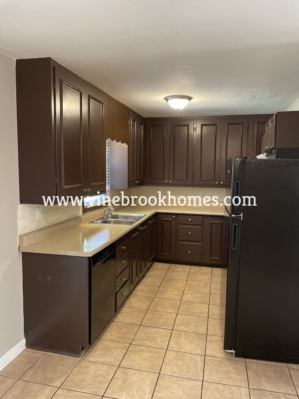 a kitchen with black cabinets and a sink and a refrigerator